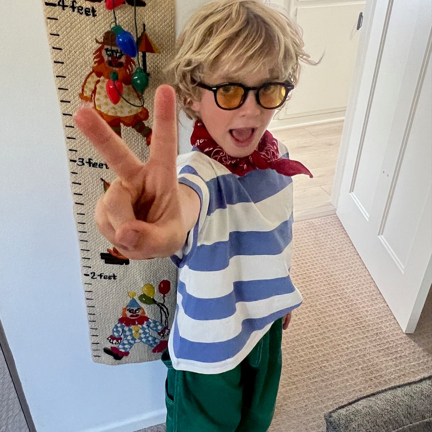 Child making a peace sign in front of a growth chart