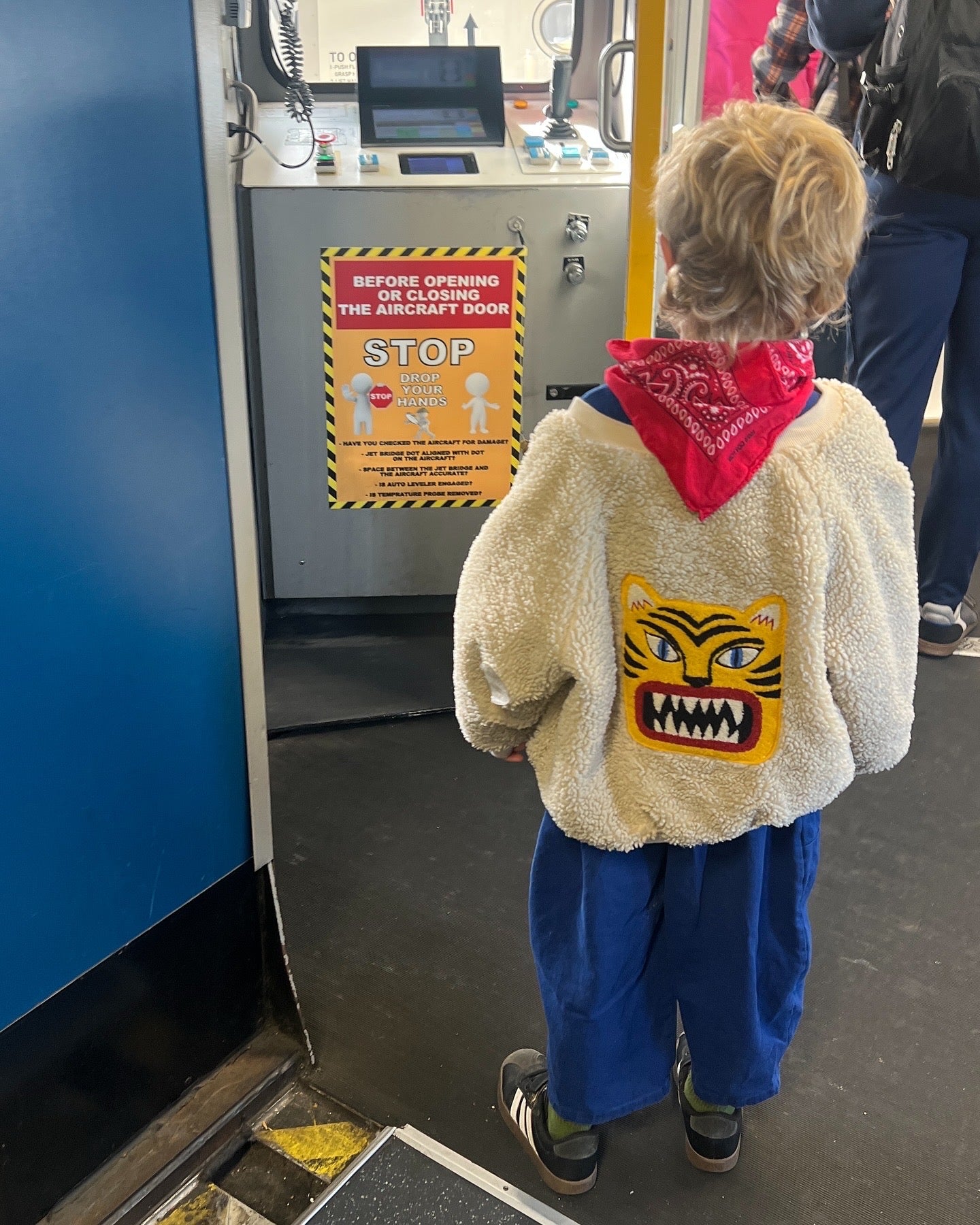 Child wearing a fluffy jacket with a tiger design at an airport gate