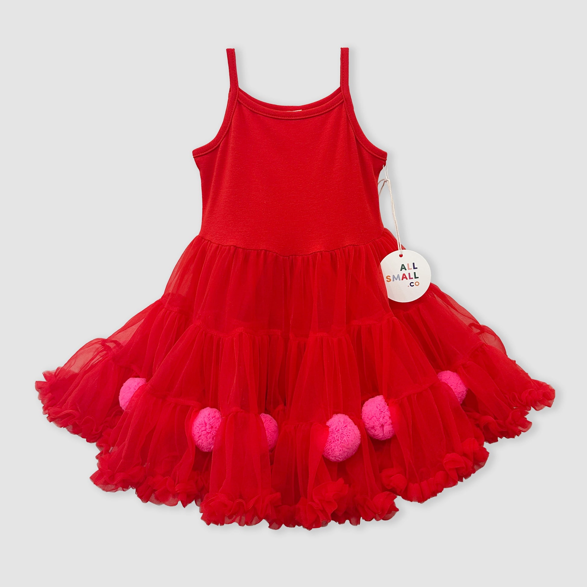 Red dress with pink pom-poms on a gray background
