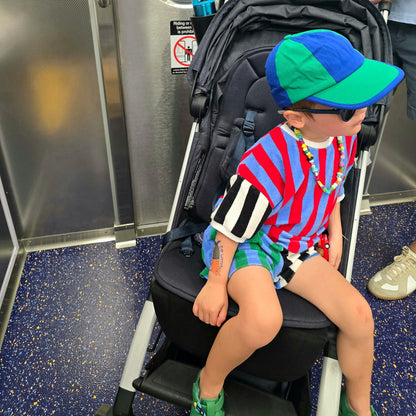 Child sitting on a stroller with a backpack in a subway car